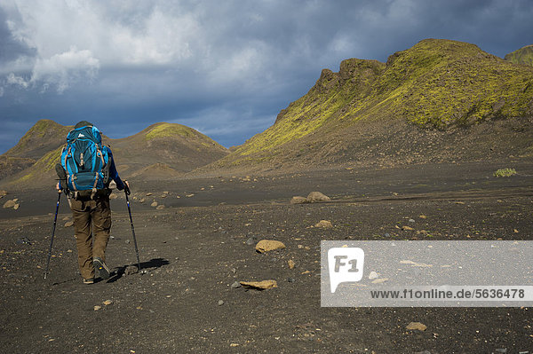 Hiker in the Black Lava Desert  with moss-covered mountains along the Laugavegur hiking trail  ¡lftavatn-Emstrur  Highland  Iceland  Europe