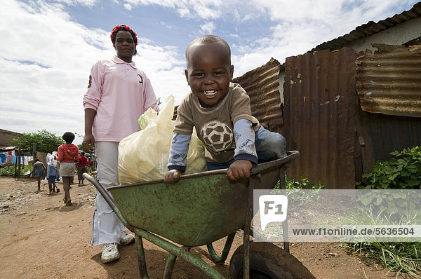 Little boy sitting in a wheelbarrow service as a pram  Soweto Township  Gauteng  South Africa  Africa