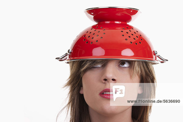 Junge Frau mit rotem Küchensieb auf dem Kopf