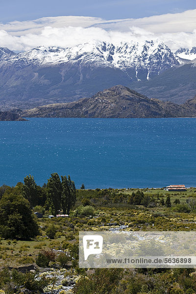 Ein einsames Farmhaus am tiefblauen Lago General Carrera  hinten die schneebedeckten weißen Anden  Carretera Austral  Ruta CH7  Panamericana Highway  Puerto Rio Tranquilo  Region de Aysen  Region de Santa Cruz  Patagonien  Chile  Südamerika  Amerika