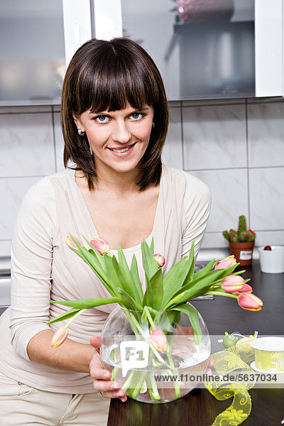 Young woman with a bunch of tulips in the kitchen