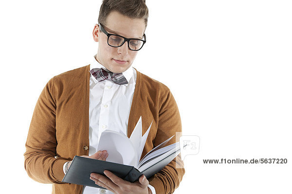 Junger Mann mit Brille und Fliege blättert in Buch  Agenda