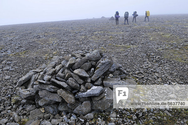 A group of hikers  Varda  also known as guard  a cairn as a trail marker  Hornstrandir  Westfjords  Iceland  Europe