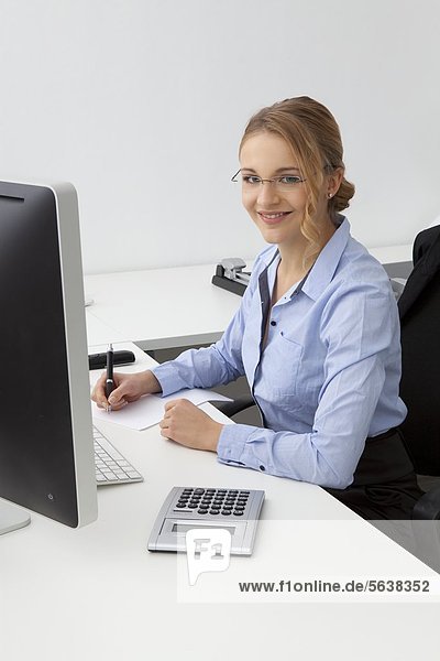 Smiling young woman sitting at desk in office