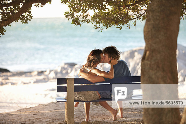 Couple kissing on park bench