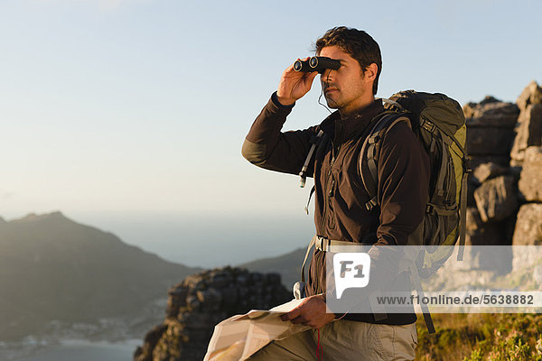Hiker using binoculars in rocky field