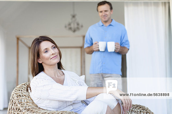 Mann bringt Freundin Kaffee auf die Veranda