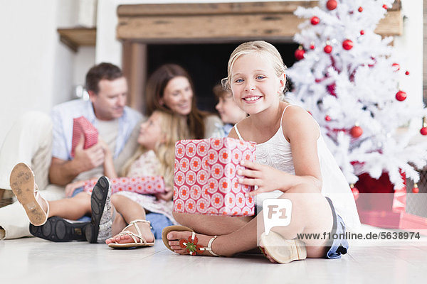 Mädchen sitzend mit verpacktem Weihnachtsgeschenk