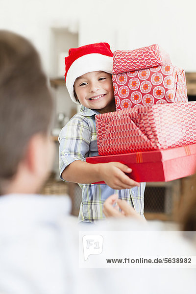 Junge in Weihnachtsmütze mit Weihnachtsgeschenken
