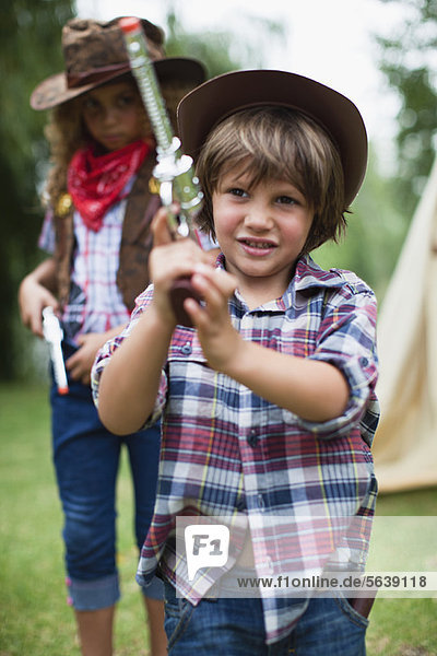 Boy in cowboy hat with toy pistol