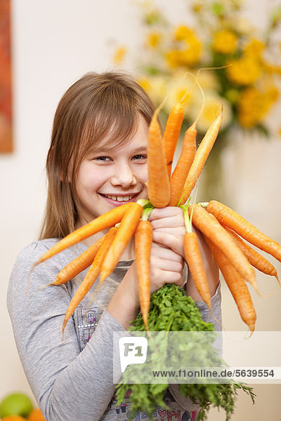 Smiling girl holding bunch of carrots