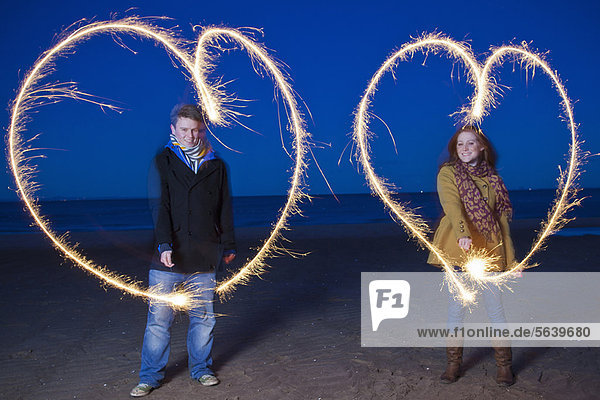 Couple playing with sparklers on beach