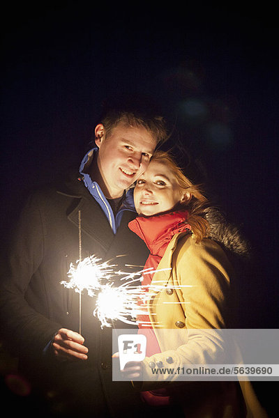 Smiling couple playing with sparklers