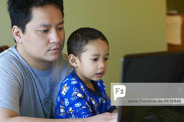 Vater und Sohn nutzen gemeinsam den Computer