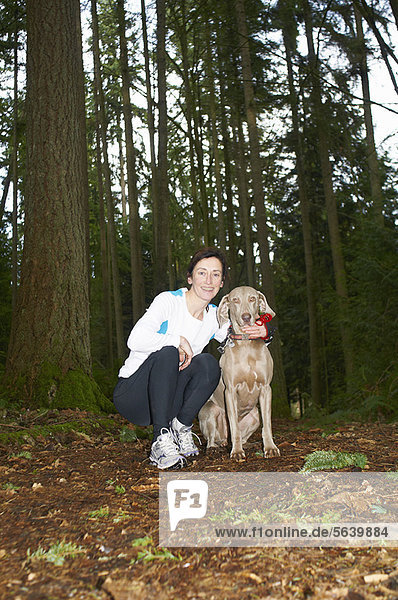 Runner smiling with dog in forest