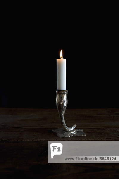 Eine angezündete Kerze im silbernen Kerzenhalter