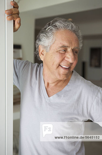 Ein fröhlicher  älterer Mann steht in einer Tür.