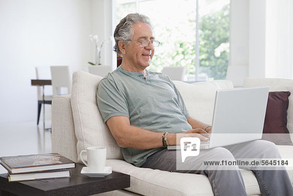 A senior man using a laptop at home