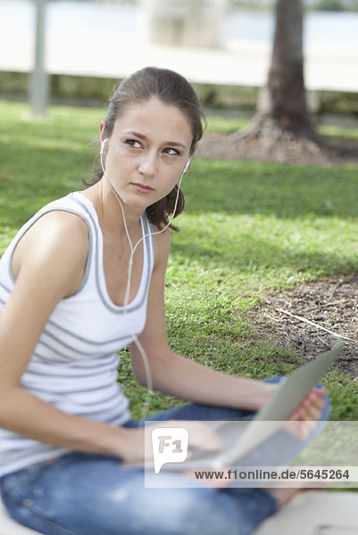 Girl with legs crossed in park using laptop