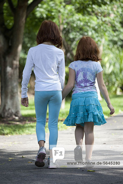 Girls walking through park hand in hand