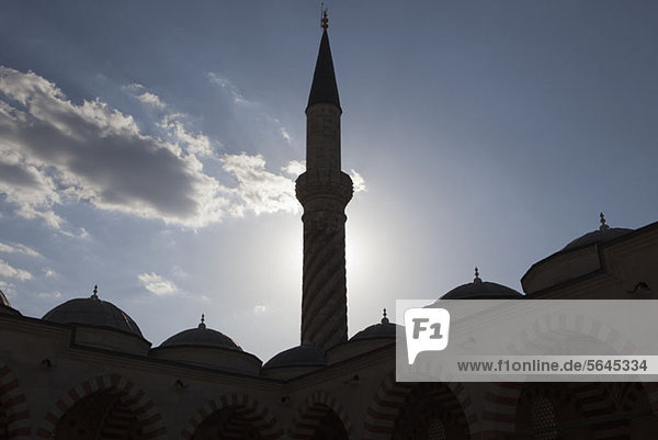 Das Minarett einer von der Sonne hinterleuchteten Moschee