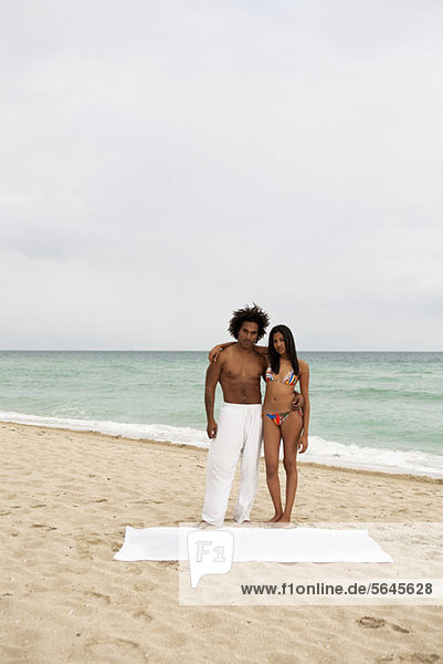 Ein attraktives junges Paar steht am Strand.