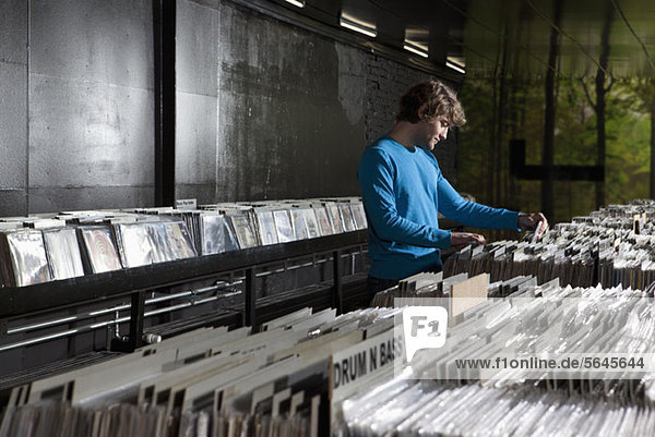 Ein junger Mann  der in einem Plattenladen nach Schallplatten sucht.