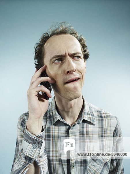 Ein Mann  der ein Handy mit einem verwirrten Gesichtsausdruck benutzt.