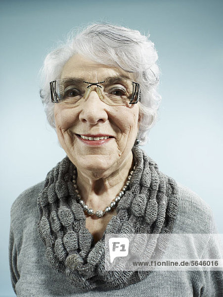 Eine elegante Seniorin lächelt die Kamera an.