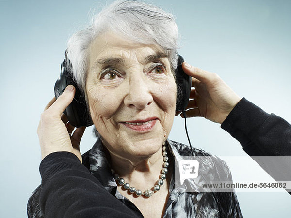 Eine Person,  die einer älteren Frau Kopfhörer aufsetzt.