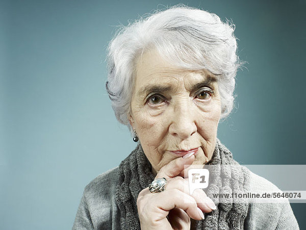 Eine ältere Frau  die mit dem Zeigefinger auf den Lippen denkt.