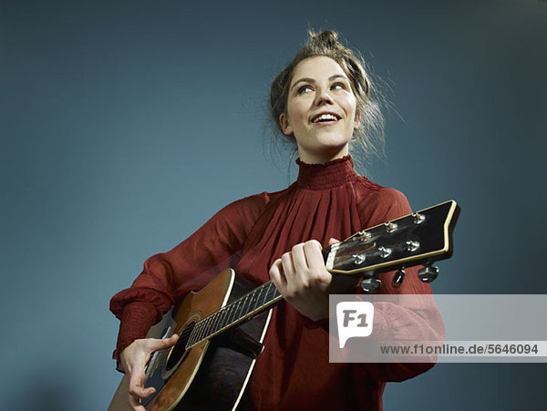 Eine junge Frau spielt eine Akustikgitarre.
