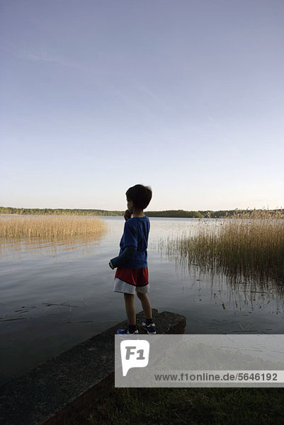Boy standing at edge of lake
