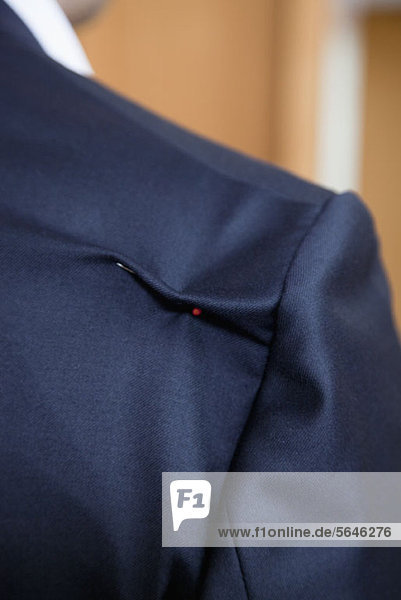 Detail einer Nadel in der Schulter einer Anzugjacke