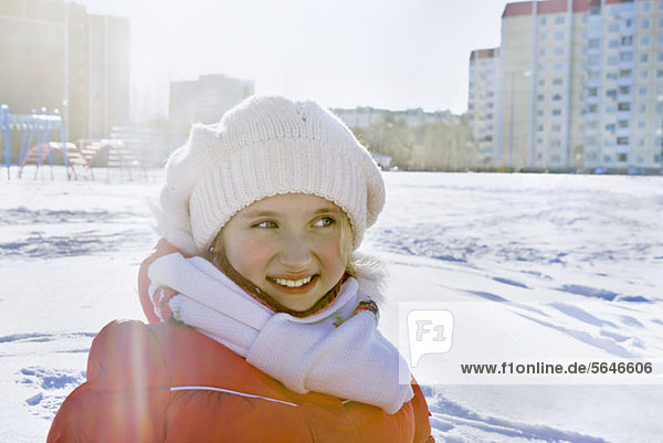 Lächelndes Mädchen in Winterkleidung im verschneiten Stadtpark