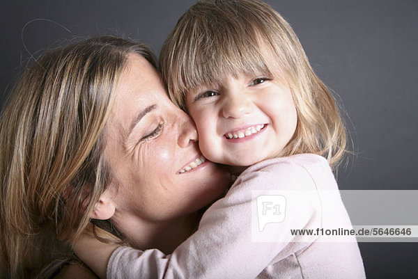 Ein lächelndes junges Mädchen umarmt ihre Mutter  Nahaufnahme