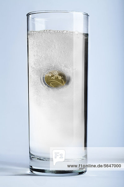 Euro Münze löst sich in Wasserglas auf