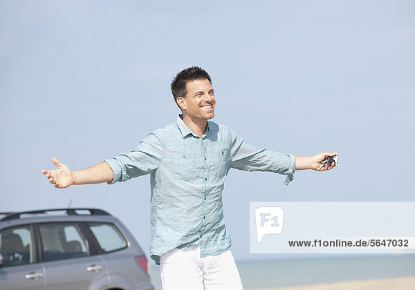 Mann mit Auto am Strand