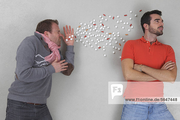Man sneezing with young man looking away
