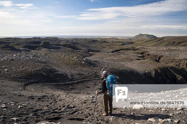 Female hiker walking in a landscape of ashes and black sand  Fimmvoer_uh·ls hiking trail  or Fimmvoerduhals - SkÛgar  Su_urland  Sudurland  southern Iceland  Iceland  Europe