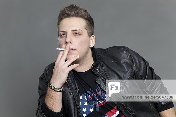 Young man wearing a leather jacket and smoking a cigarette  portrait