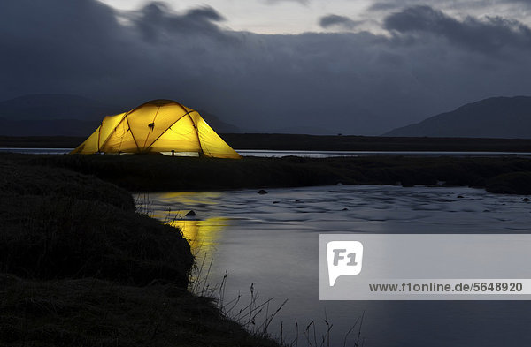 Gelbes erleuchtetes Expeditionszelt  Trekkingzelt  an einer Flussmündung ins Meer  Abendstimmung  Isle of Skye  Schottland  Großbritannien  Europa