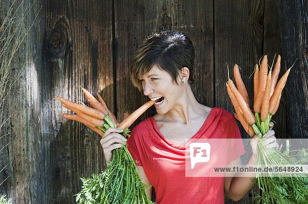 Österreich  Salzburg  Flachau  Junge Frau hält Karotten