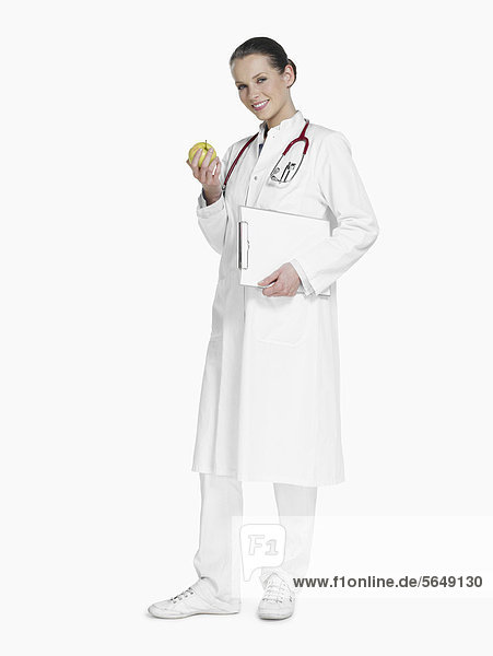 Ärztin mit Stethoskop  Klemmbrett und grünem Apfel  lächelnd  Portrait