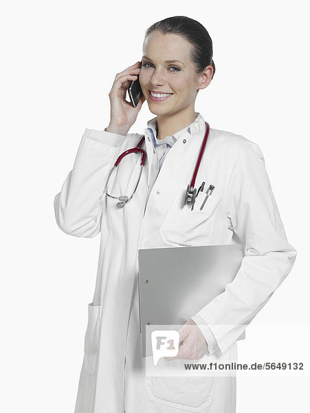 Ärztin auf dem Handy mit Stethoskop und Klemmbrett  lächelnd  Portrait