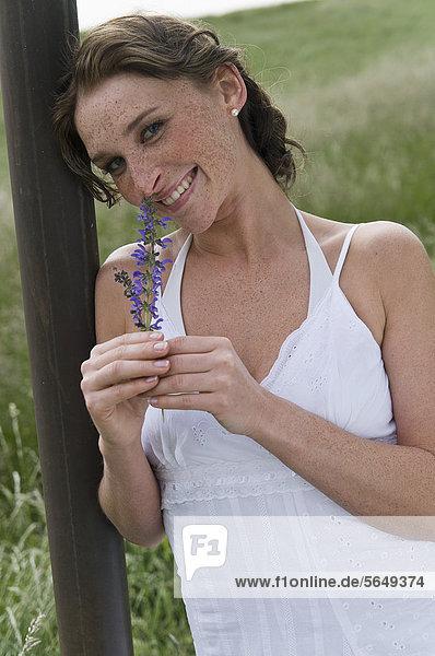 Germany  North Rhine Westphalia  Duesseldorf  Young woman holding flower  smiling  portrait