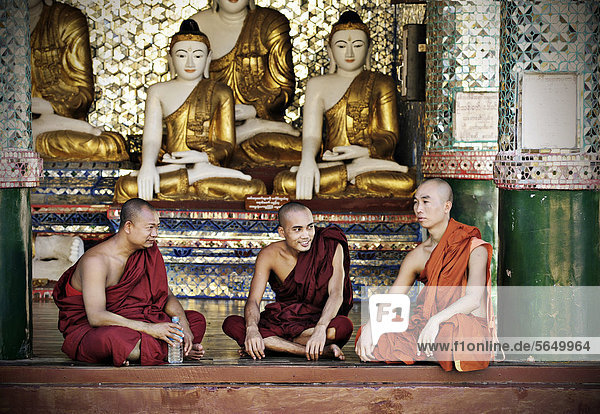 Buddhist monks sitting in front of Buddha statues in the Shwedagon Pagoda  Yangon  Burma also known as Myanmar  Southeast Asia  Asia