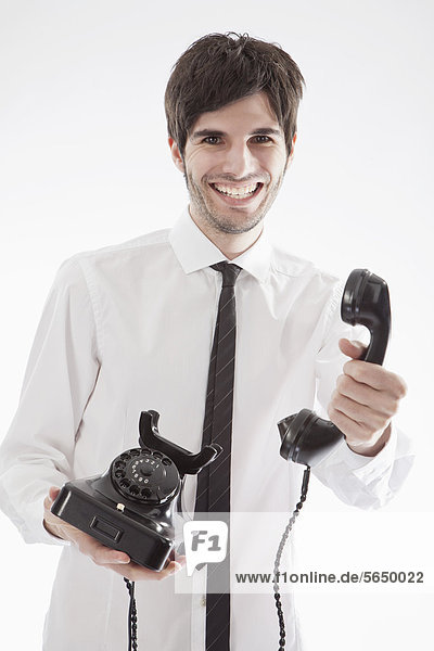 Junger Mann mit antikem Telefon  lächelnd  Portrait