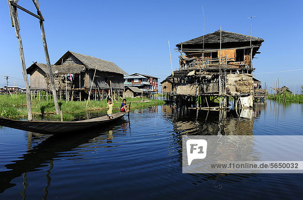 Stilt houses and two children in a boat on Lake Inle  Burma also known as Myanmar  Southeast Asia  Asia