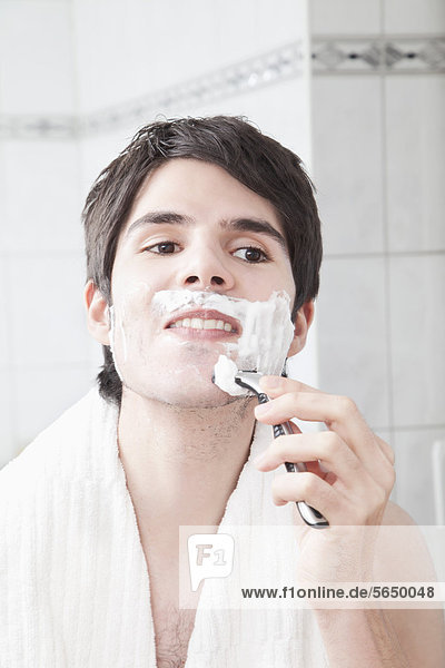 Young man doing shaving in bathroom
